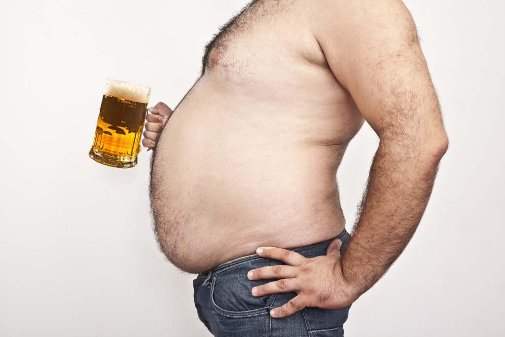An obese man carrying a beer mug